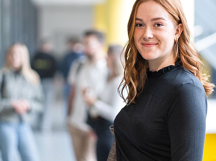 Junge Schülerin ist zu Besuch auf dem DHBW CampusTag und lächelt in die Kamera.