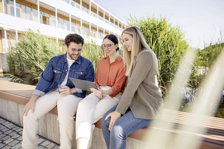 Wirtschaftsinformatik-Studierende bei dmTECH arbeiten am iPad auf Terasse des dmTECH-Unternehmenssitzes.